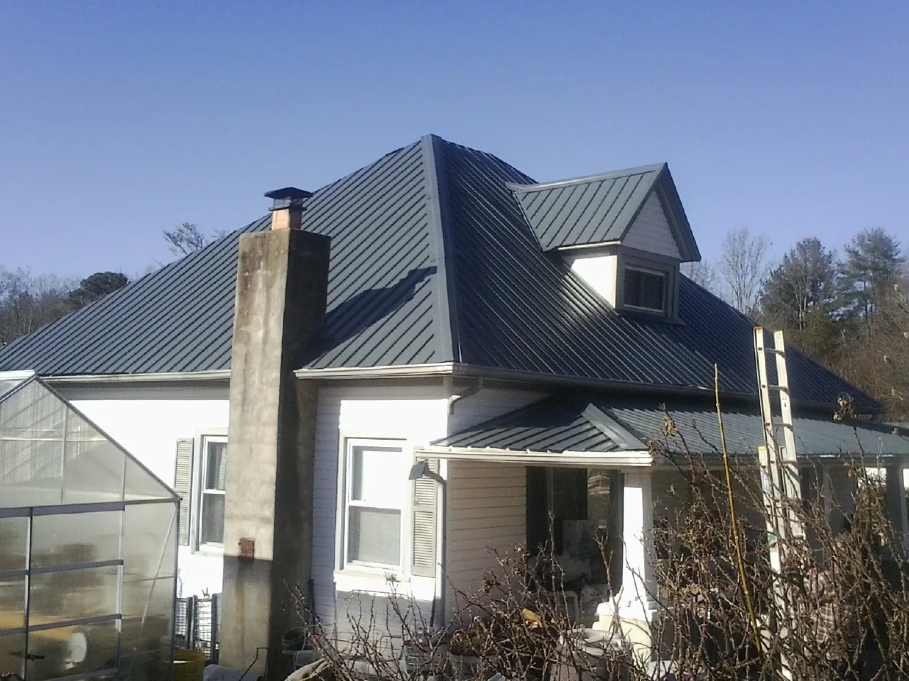 Dark blue standing seam metal roof on a white farmhouse with dormer — Slate & Tile Roof Repair by Roofing Brothers in Imler