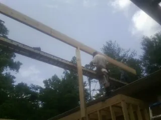 Carpenter setting a ridge beam over a new addition frame — Ice Dam Removal by Roofing Brothers in Imler