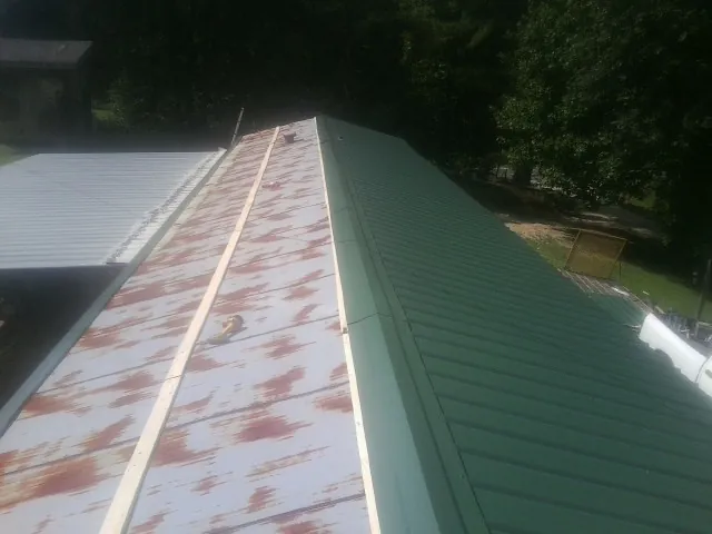 Old rusted panels beside newly installed green metal roofing — Wind Damage Roof Repair by Roofing Brothers in Imler
