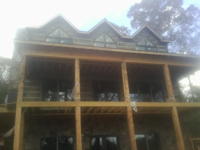 Dormers and porch framing on a large log home under construction — Roof Coating work by our crew in Imler