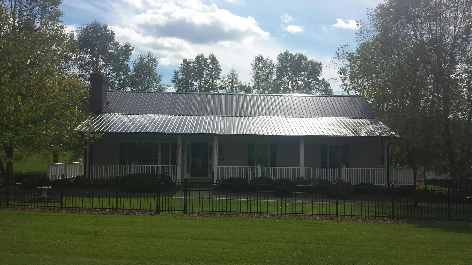Gray metal roof on a brick ranch with a full width front porch — Gutter Guard Installation work by our crew in Imler