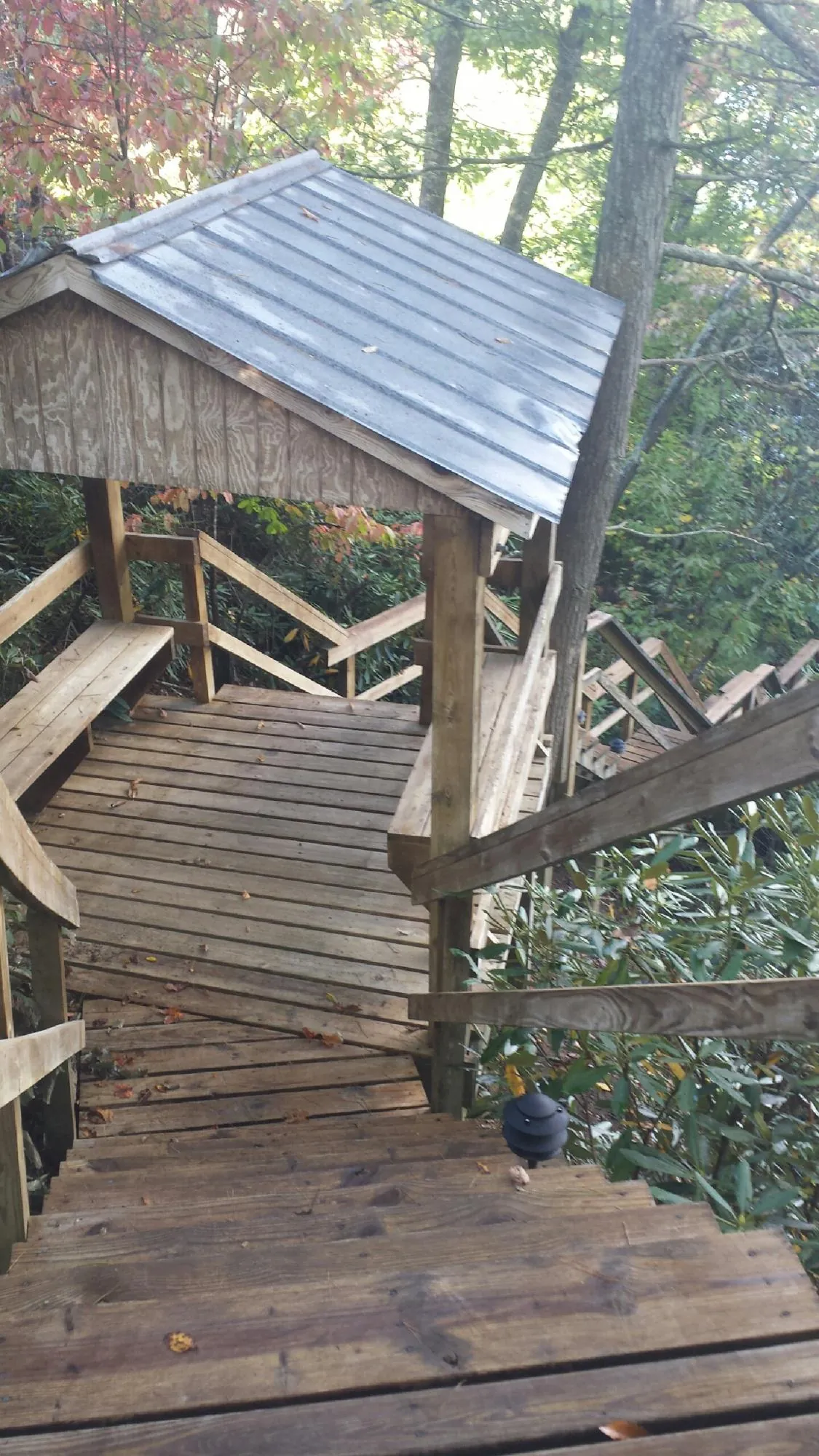 Metal roofed shelter over wooden steps on a wooded walkway — Skylight Repair & Installation work by our crew in Imler