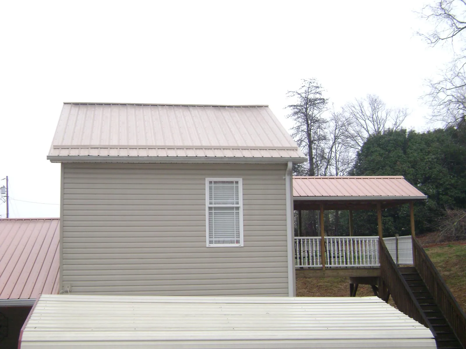 Tan metal roofs on a two story addition and attached porch, from a Roof Replacement job in Imler