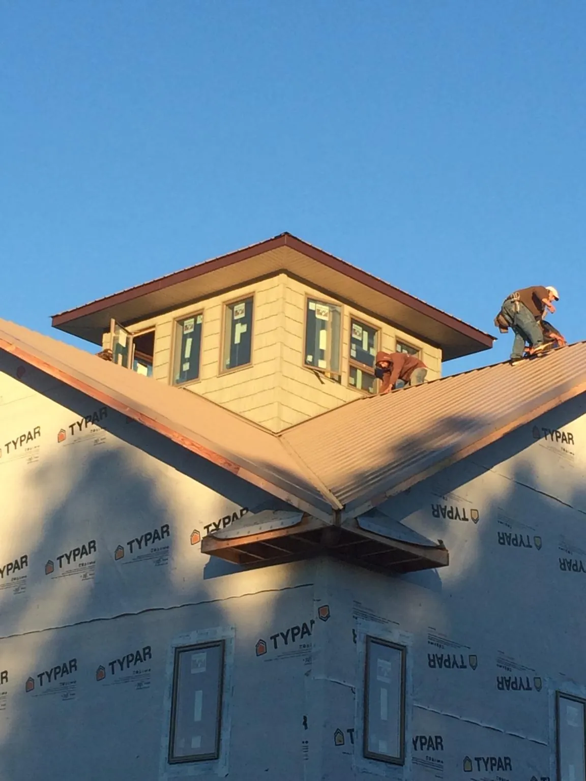 Roofers working around a rooftop cupola on a new metal roof at sunset — Roof Waterproofing in Imler by Roofing Brothers